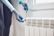 © astrosystem - Handyman with gloves fixing and bleeding air from central heating gas radiator system at home.