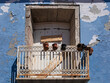 Fenêtre au balcon étroit et rouillé d'un vieil immeuble délabré et insalubre. Façade à la peinture écaillée, aux volets en bois fermés et condamnés. Sud de la France, vielle ville de Sète.