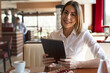 © Milana - A young beautiful woman is listening music on her tablet while sitting in the cafe