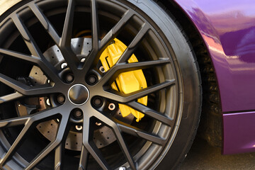 Alloy wheel with calipers and racing brakes of the sport car. Racing brake disc and low profile tyres. Race car test driving. Lower-profile tires of drag and drift cars. High-performance sports cars.