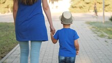 Mom Leads Boy By Hand, Custody Of Little Child, Happiness Of Motherhood With Her Son, Mother Walks With Kid In City Park In Open Air, Life With Parent, Look After And Take Time For Baby On Weekends