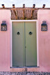 Green Door. Isolated. Front door with door knockers and exterior lanterns on pink wall . 