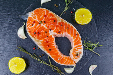 Wall Mural - Raw salmon steak with spices on black slate. Top view