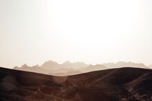 Desert Landscape. Stony Hills In The Foreground With The Silhouette Of Rocky Mountains. Sun Glare From Sunset Light. Space, Fantastic Atmosphere In The Sahara Desert