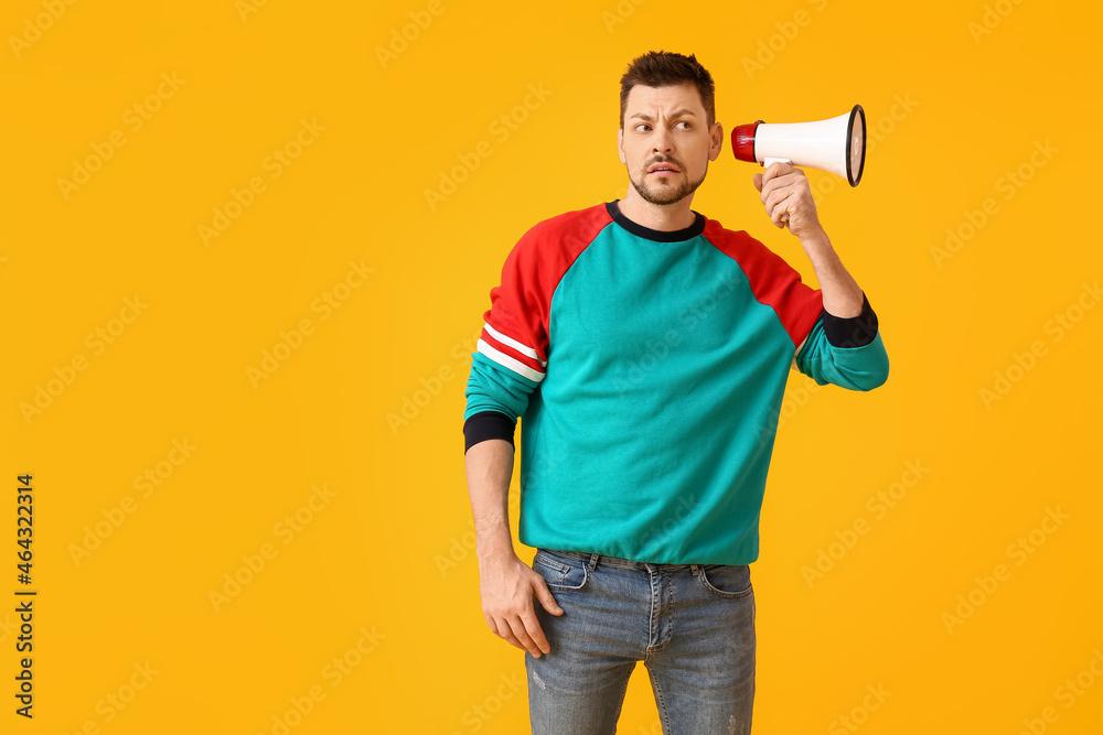 Emotional man with megaphone on color background