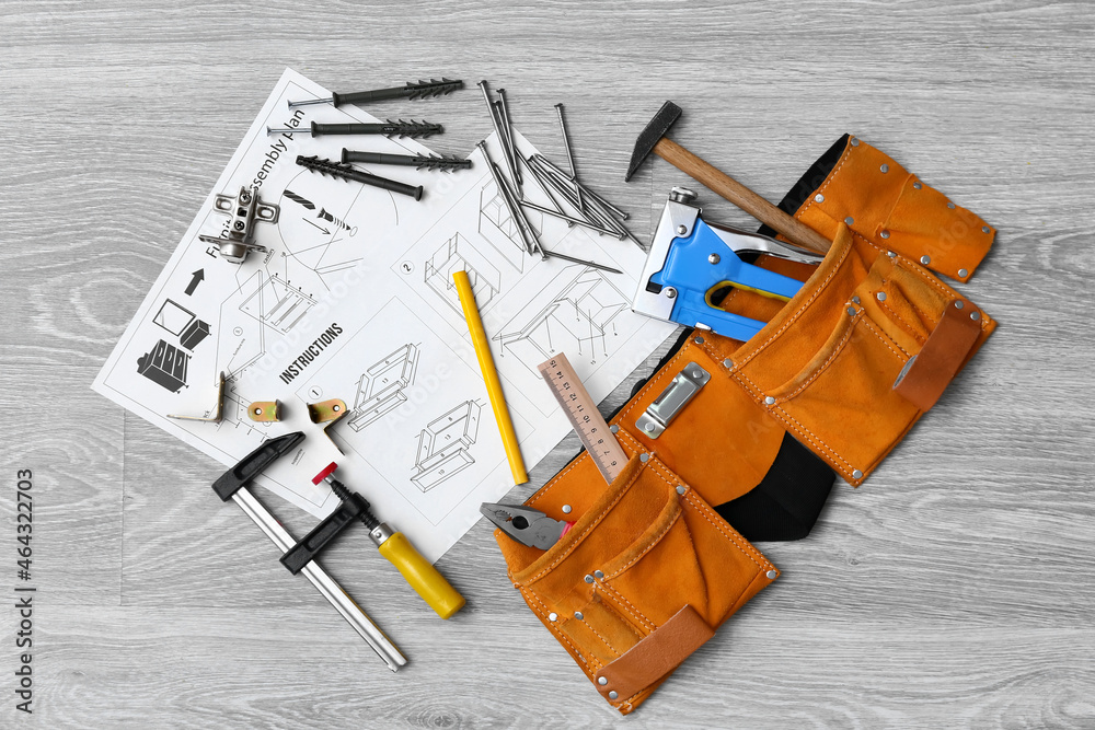 Furniture assembling instructions and scattered tools on grey wooden background