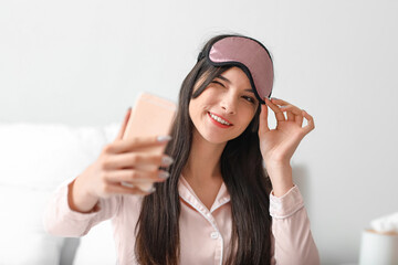 Sticker - Pretty young woman with sleeping mask taking selfie in bedroom