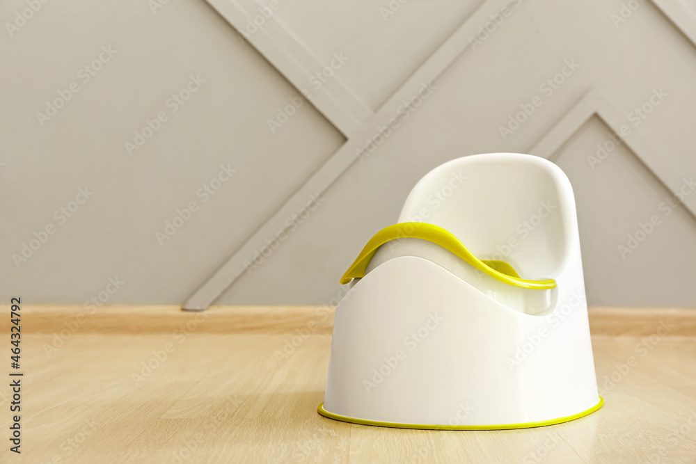 Potty on wooden floor near grey wall
