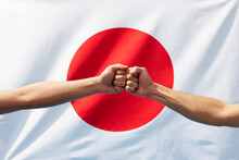 日本の国旗の前で力強くこぶしを合わせる二人