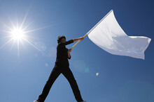青空と太陽の下で白い旗を振る男性