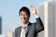 © amanaimages - ビジネススーツを着て手を上げている笑顔の男性