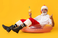 Santa Claus With Swimming Ring And Cocktail Showing Thumb-up On Color Background