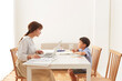 © amanaimages - ダイニングテーブルで在宅ワークをする女性と勉強する男の子