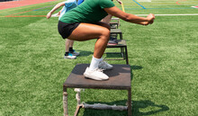 Athletes Jumping On To Plyo Boxes Outdoors On A Turf Field