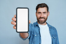 Satisfied Smiling Man Showing Mobile Phone Blank White Screen Mockup To Camera