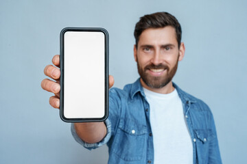 Wall Mural - satisfied confident smiling adult businessman showing mobile phone blank white screen mockup to came