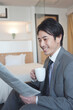 © amanaimages - ホテルの部屋で新聞を読むビジネスマン