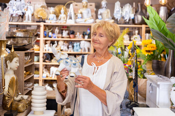 Senior woman buyer choosing indian souvenir statue of Elephant at the household goods store