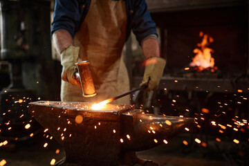 Close-up of blacksmith manually forging the molten metal in the workshop