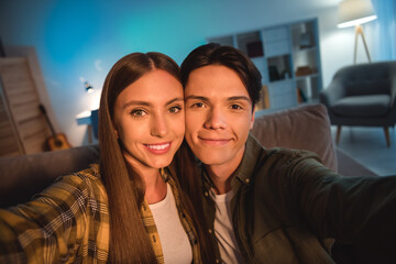 Poster - Photo of sweet charming young couple wear casual shirts smiling tacking selfie indoors house room