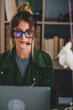 © simona - Young businesswoman wearing eyeglasses and headset while using laptop at workplace, Beautiful woman using laptop. woman wearing headset with microphone, looking at laptop screen