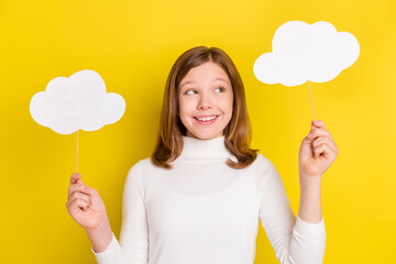 Poster - Photo of charming dreamy young small girl look hold hands clouds weather isolated on yellow color background