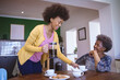 © Wavebreak Media - Smiling african american senior woman with adult daughter drinking coffee in kitchen