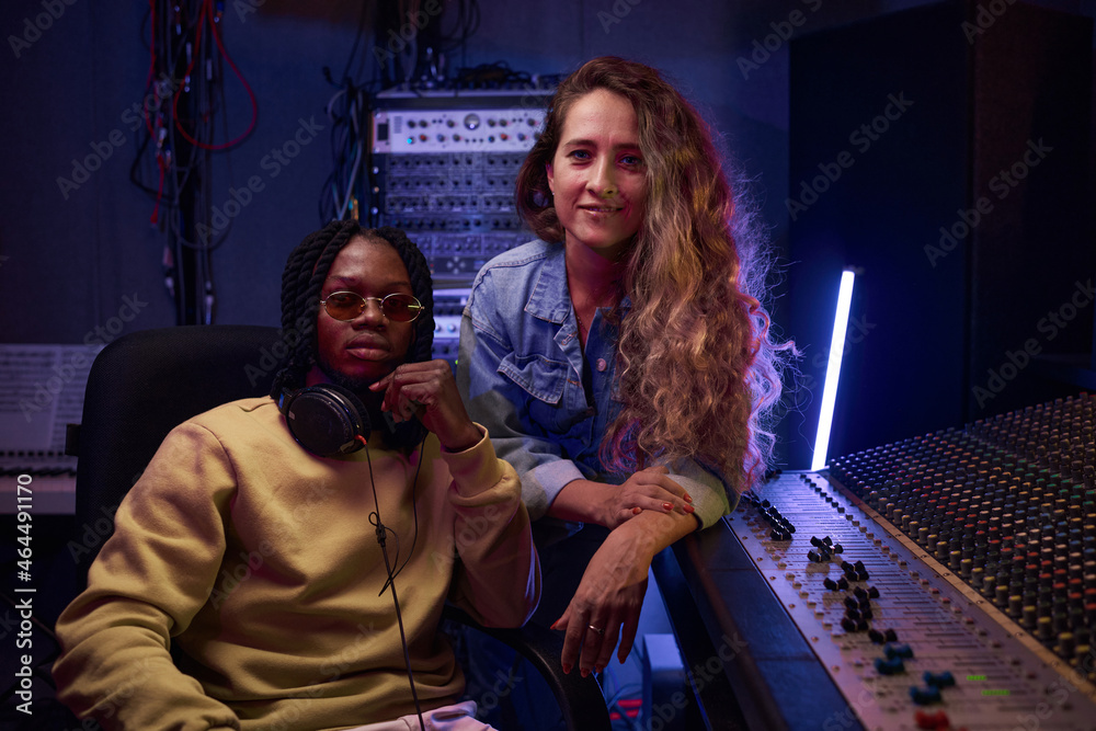 Portrait of young singer with her musical producer looking at camera ...