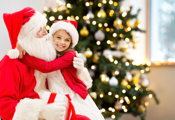 Poster - winter holidays, celebration and people concept - smiling girl hugging santa claus at home over christmas tree lights on background