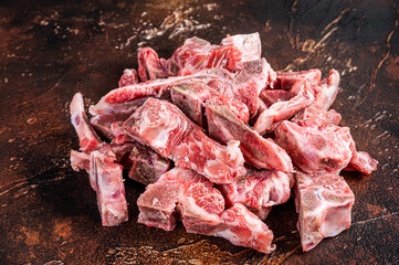 Wall Mural - Raw meat on the bone diced for stew. Dark background. Top View