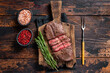 Fried Top Blade or flat iron roast beef meat steaks on wooden board with rosemary. Dark wooden background. Top View