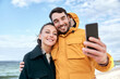 © Syda Productions - technology, relationships and people concept - happy couple with smartphone on autumn beach