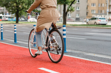 traffic, city transport and people concept - woman riding bicycle along red bike lane or two way road on street