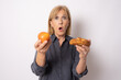 © Danko - Amazed elderly woman holding an apple and croissant isolated over white background.