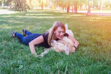 Wall Mural - woman hugs her retriever dog while lying on the grass