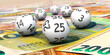 Lottokugeln liegen auf Euroscheinen