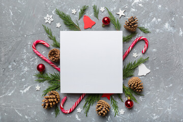 Wall Mural - Flat lay Christmas composition. square Paper blank, pine tree branches, christmas decorations on Colored background. Top view, copy space for text