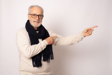 Wall Mural - Positive senior man pointing with hand and finger to the side isolated over white background.