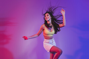 Wall Mural - Portrait of gorgeous cheery dreamy girl dancing having fun isolated over vivid violet purple neon color background