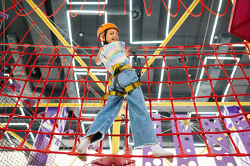 Wall Mural - Little girl holding on to the ropes, zip line