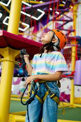 Wall Mural - Cheerful little girl in helmet poses on zip line