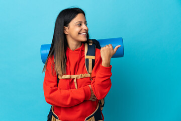 Wall Mural - Young mountaineer woman with backpack pointing to the side to present a product