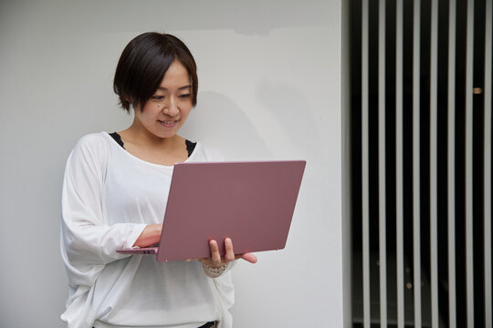 オフィスでノートパソコンを持ちながら仕事をする日本人女性