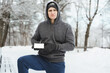 Young man athlete showing smartphone with a blank screen during winter workout