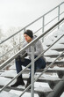 Portrait of handsome athletic man sitting on stairs before his winter workout outside