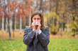 © Анжелла Антоновская - A girl stands on the street in a park in autumn and blows her nose in a handkerchief