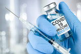 Fototapeta Zwierzęta - Hand in blue medical gloves holding a syringe and vaccine vial with Covid 19 Vaccine Booster text, for Coronavirus booster shot.
