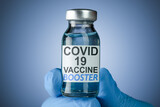 Fototapeta Zwierzęta - Hand in blue medical gloves holding a vaccine vial with Covid 19 Vaccine Booster text, for Coronavirus booster shot.