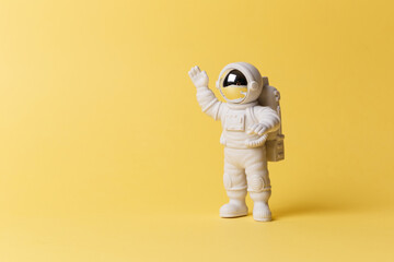 plastic toy figure astronaut on a yellow background. copy space. close-up. the concept of space and 