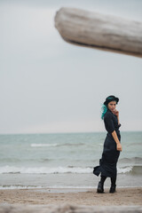 Wall Mural - beautiful woman with blue hair and hat walks on the windy beach